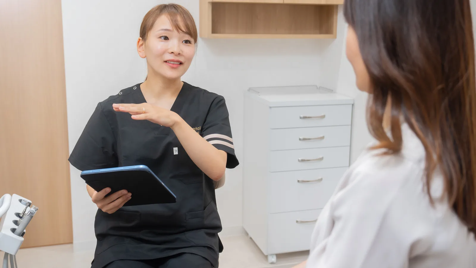 女性スタッフがタブレットを見せながら患者に説明している様子